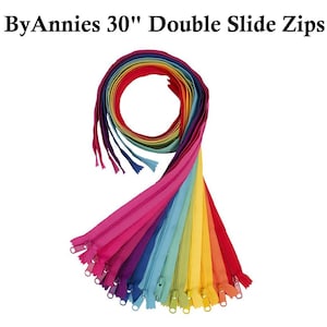 May include: A selection of rainbow-colored double slide zippers, each measuring 76 cm in length. The zippers are displayed in a fan shape, showcasing the range of colors. The text "ByAnnie's 30" Double Slide Zips" is visible at the top.
