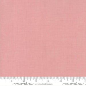 May include: A close-up of a piece of pink fabric with a subtle woven texture. A ruler is at the bottom of the image, with the word "moda" and the website address www.modafabrics.com printed on it.