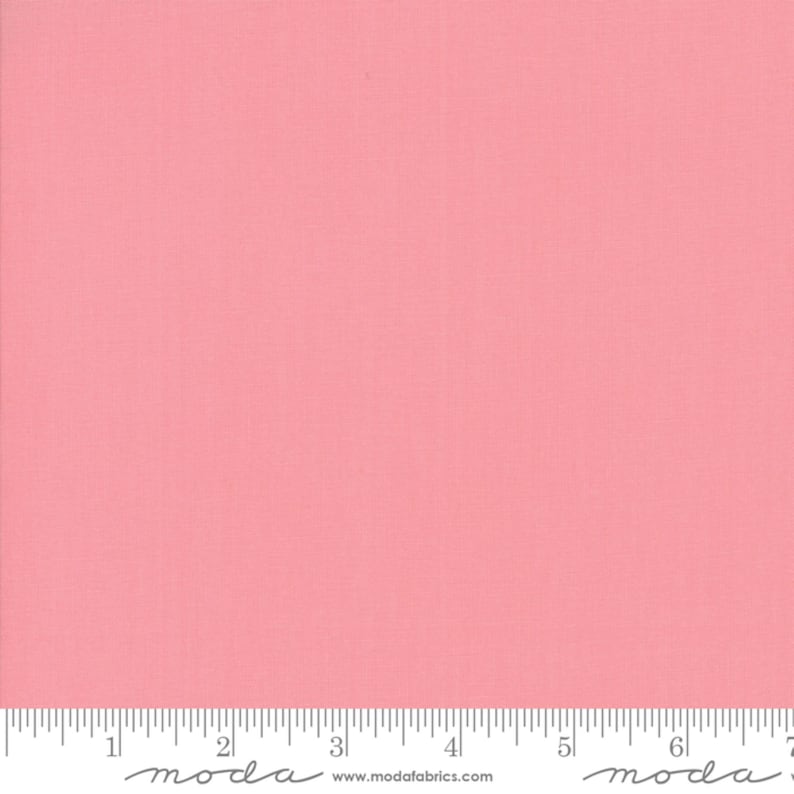 May include: A solid pink fabric swatch with a ruler showing 7 inches. The ruler has the word "moda" printed on it.