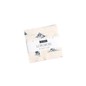 May include: A cream-coloured fabric square with a blue and white illustration of a mountain range and a small cabin. The fabric has a label that reads "LONGSHORE by JANET CLARE".