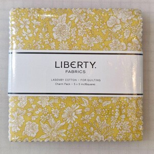 Könnte beinhalten: Ein Stapel gelber Stoffquadrate mit Blumenmuster, in klarem Kunststoff verpackt. Der Stoff hat ein weißes Blumenmuster. Das Etikett lautet "LIBERTY FABRICS" und "LASENBY COTTON - FOR QUILTING Charm Pack - 12,7 x 12,7 cm Quadrate."
