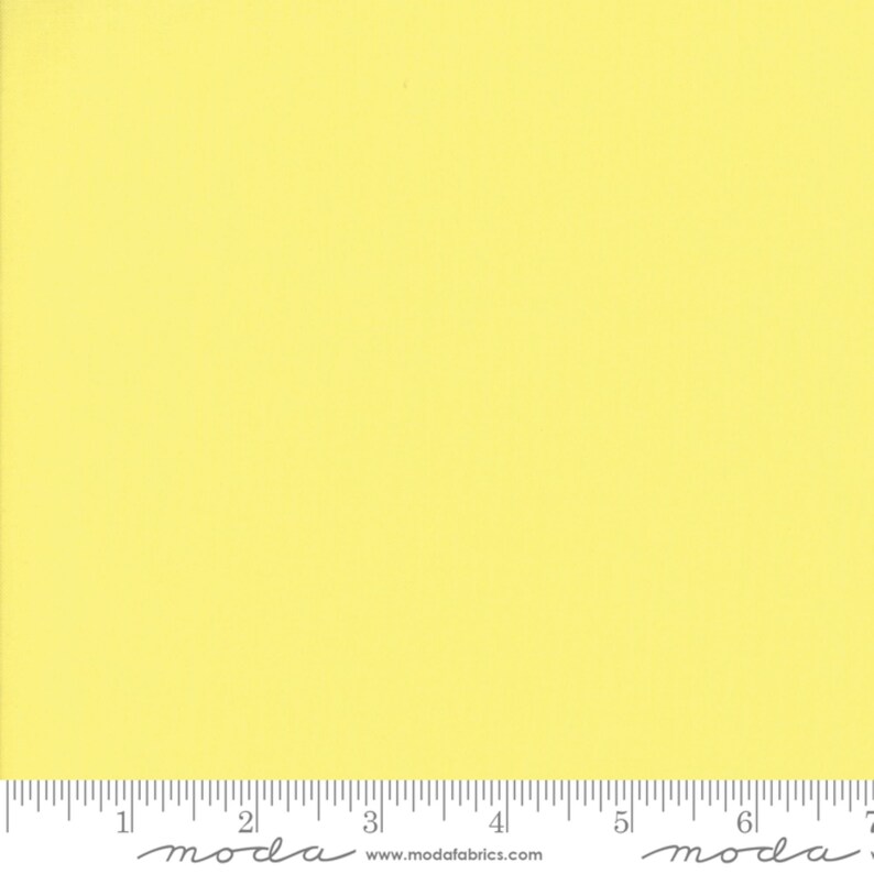 May include: A solid yellow fabric swatch with a ruler showing 7 inches. The ruler has the word "moda" printed on it.
