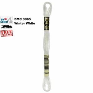 Puede incluir: Un ovillo de hilo de bordar DMC 3865 Winter White. El hilo blanco está envuelto alrededor de una etiqueta negra y dorada con el logotipo de DMC y los detalles del hilo. La etiqueta también incluye un código de barras y el número 3865.