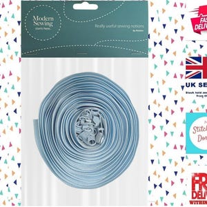 May include: A spool of light blue sewing notions, likely zipper tape, is the central focus. The packaging includes the text "Modern Sewing starts here... Really useful sewing notions." The background is a white surface with a colorful triangle pattern.