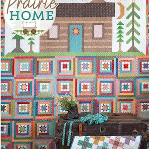 Può includere: Una colorata trapunta con un design a capanna di tronchi e le parole "Prairie Home". La trapunta presenta una capanna, alberi e un carro. Sotto, è esposta una trapunta patchwork con motivi a stella.