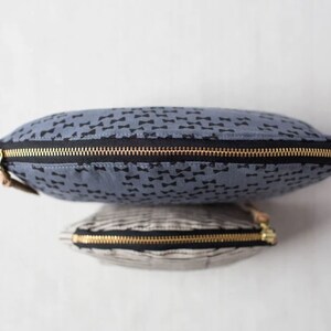 May include: Two zippered pouches, one blue with a black bowtie pattern and one striped in black and white.