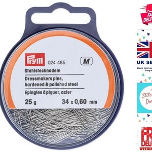 Puede incluir: Un recipiente de plástico redondo lleno de 25 alfileres de sastre plateados, tamaño M, 34 mm x 0,60 mm. El recipiente está etiquetado "Prym 024 485 Stahistecknadeln Dressmakers pins, hardened & polished steel Epingles à piquer, acier 25 g 34 x 0,60 mm".