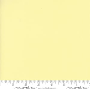 May include: A solid yellow fabric swatch with a ruler showing 17.8 cm. The ruler has the word "moda" printed on it.
