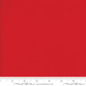 May include: Solid red fabric swatch with a white ruler marked in inches. The ruler has the word "moda" printed on it.