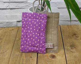 May include: Two handmade dishcloths, one purple with pink polka dots and one natural linen with a brown button and the text "The Stitch Handcrafted".