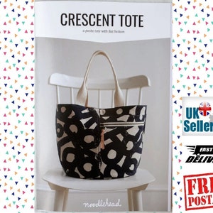 May include: A black and white tote bag with a geometric pattern. The tote bag is sitting on a white chair. The text "CRESCENT TOTE" and "a petite tote with flat bottom" is printed on the page. The text "noodlehead" is printed at the bottom of the page.