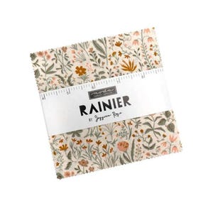 Könnte beinhalten: Ein Stapel Stoffquadrate mit einem floralen Muster in Creme-, Grün- und Orangetönen. Der Stoff ist mit einem weißen Band mit der Aufschrift "RAINIER by Jessica Rose" und einer Lineal-Grafik umwickelt.