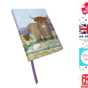 May include: A blue and green journal with a colorful patchwork design featuring a brown Highland cow. The journal has a purple ribbon bookmark and the text "The Stitchery Dorset" is printed on the cover.
