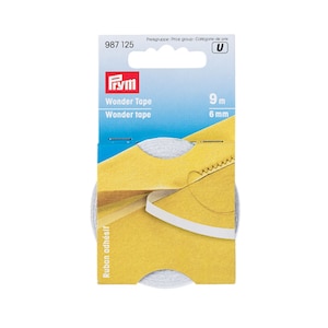 May include: A roll of Prym Wonder Tape, a 9-metre long, 6-millimetre wide adhesive tape for sewing and crafts. The tape is shown on a yellow and blue package with the text "Wonder Tape" and "Ruban adhésif".
