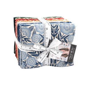 Op de afbeelding: Een stapel van 12 fat quarters stof met een blauwe en witte bloemenprint op een crème achtergrond. De stof is vastgebonden met een wit lint en een meetlint. De stof is gelabeld met "Moda Fabrics - Supplies".