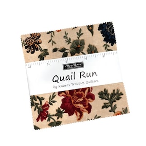 Könnte beinhalten: Ein Stapel quadratischer Stoffstücke mit beigem Hintergrund und Blumenmustern in Rot, Dunkelblau und Grün. Ein weißes Papierband umschließt die Mitte mit dem Text Quail Run by Kansas Troubles Quilters und einem 12,7 cm Lineal.