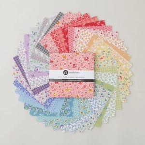 Peut inclure: Un ensemble de carrés de tissu Sweet Things d'Andover Fabrics disposés en cercle. Les carrés présentent des motifs floraux et à motifs dans diverses couleurs, dont le rose, le bleu et le jaune. Le tissu mesure 7,6 cm x 7,6 cm et est en 100 % coton.