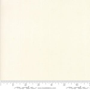 May include: Cream-colored fabric with a subtle texture, ideal for quilting or crafting. The fabric has a ruler along the bottom edge with the word "moda" printed on it. The website address www.modafabrics.com is also visible.