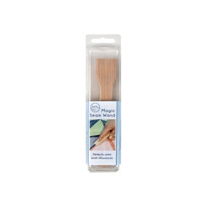 Op de afbeelding: Een houten naadstrijkstok in een doorzichtige plastic verpakking. De verpakking heeft de tekst "Magic Seam Wand" en "Perfectly press seam allowances".