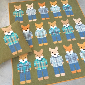 Puede incluir: Un juego de edredón y almohada verdes con un patrón repetido de personajes de zorro. Cada zorro lleva una camisa a cuadros y vaqueros azules. El edredón y la almohada tienen un patrón texturizado similar a la veta de la madera.