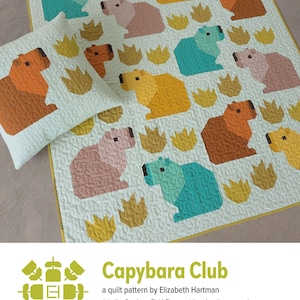 May include: A light blue quilt and pillow set featuring a repeating pattern of geometric capybara figures in shades of orange, yellow, pink, and teal. The quilt and pillow have a light green background with yellow accents and a quilted texture. The text "Capybara Club" is visible.
