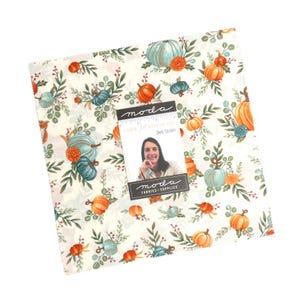 Puede incluir: Un conjunto de cuadrados de tela con un estampado de calabazas de temática otoñal en naranja, verde azulado y crema. La tela presenta calabazas, flores y follaje. Una etiqueta con el texto "I love fall more than all" y una foto de Deb Strain está adjunta.