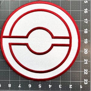 May include: Circular white patch with a red border and a stylized red design in the center. The design includes a circle, a horizontal line, and a curved shape. The patch is approximately 4 inches in diameter.