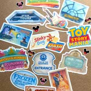 May include: A collection of colorful stickers featuring various theme park attractions, including Star Tours, Toy Story Mania, Mickey & Minnie's Runaway Railway, Frozen, Indiana Jones, and Beauty and the Beast, interspersed with small Mickey Mouse icon stickers.
