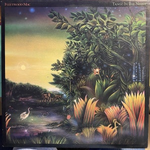 May include: Fleetwood Mac's "Tango in the Night" album cover. The artwork features a vibrant jungle scene with lush green foliage, a serene pond, and a sunset sky. The album title is displayed at the top right.