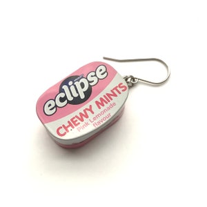 May include: Pink and white Eclipse Chewy Mints earring with a silver hook. The mint tin features the text "Eclipse Chewy Mints Pink Lemonade flavour" and the Wrigley's logo.