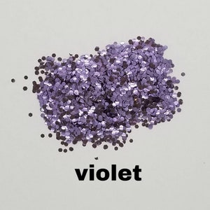 May include: A pile of loose purple glitter, with the word "violet" written below it.