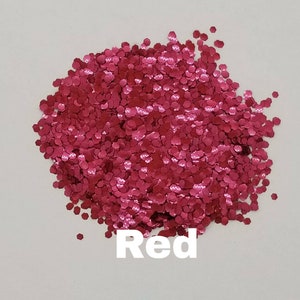 May include: A pile of red glitter, with a hexagonal shape. The glitter is on a white background. The word "Red" is written below the glitter.