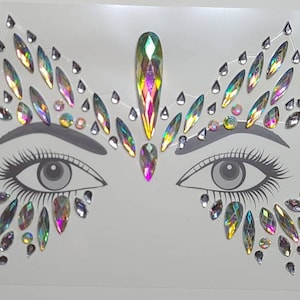 May include: A sheet of iridescent face jewels in the shape of a butterfly with a large jewel in the center. The jewels are arranged around two drawn eyes. The sheet is labeled with the letter "B".