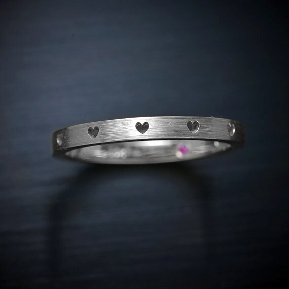 Platinum wedding Band with Cutouts hearts, starts or crosses a pink sapphire inside.