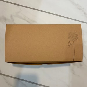 May include: A brown cardboard box with a simple design of a dandelion on the top right corner.