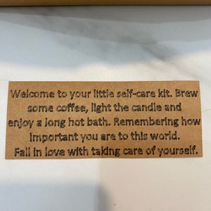 May include: A brown card with the text "Welcome to your little self-care kit. Brew some coffee, light the candle and enjoy a long hot bath. Remembering how important you are to this world. Fall in love with taking care of yourself."