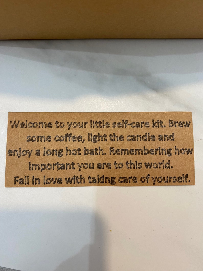 May include: A brown card with the text "Welcome to your little self-care kit. Brew some coffee, light the candle and enjoy a long hot bath. Remembering how important you are to this world. Fall in love with taking care of yourself."