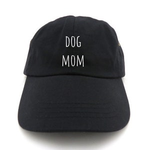 May include: Black baseball cap with the words "DOG MOM" in white block letters. The cap has a curved brim and a fabric strap in the back for adjustment. The hat is made of a soft, durable material.