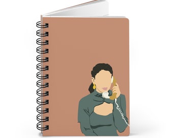 May include: Spiral-bound notebook with a terracotta-colored cover featuring an illustration of a person holding a vintage telephone. The person is wearing a teal-colored top and gold earrings. The notebook's spiral binding is black.