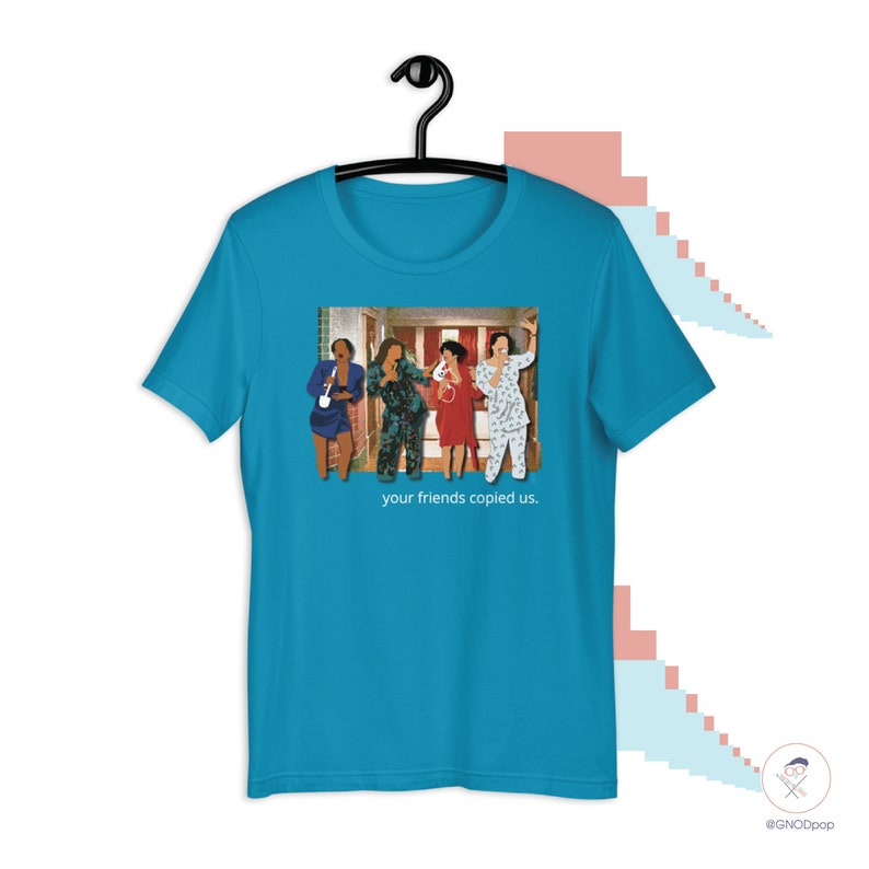 May include: A turquoise blue t-shirt with a graphic of four people in a hallway. The graphic is a still from a movie or TV show. The text "your friends copied us." is printed below the graphic.