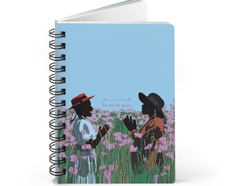 May include: A blue spiral notebook with a colorful illustration of two people standing in a field of flowers. The text "Love must be the Us never part..." is printed on the cover.