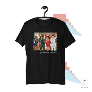 May include: Black t-shirt with a graphic of five people in pajamas standing in a hallway. The text "your friends copied us." is printed below the graphic.