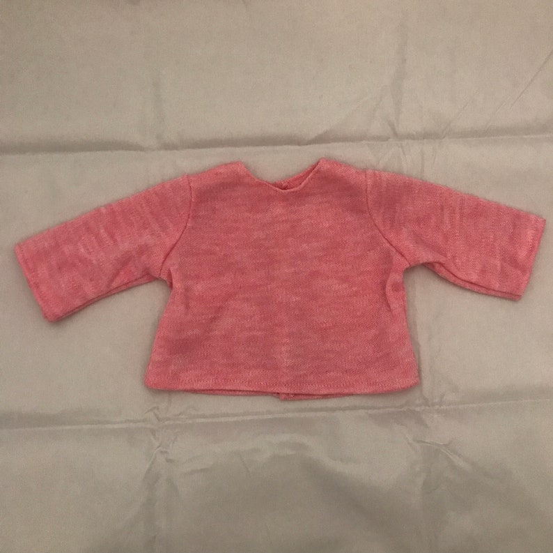 May include: A pink knitted sweater with long sleeves.