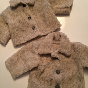 May include: Two cream-colored fleece jackets with button closures. The jackets have a fuzzy texture and are laid out on a white surface.