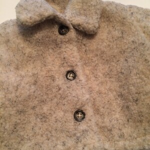 May include: A white, fluffy, faux fur jacket with a collar and four black buttons.