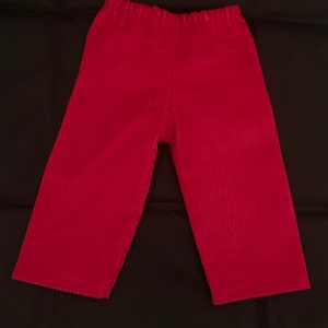 May include: A pair of red corduroy trousers with a wide leg and elastic waistband.