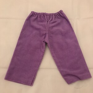 May include: Purple corduroy trousers with a wide leg and elastic waistband.