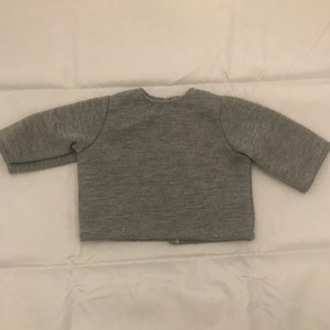 May include: A gray long-sleeved cardigan with a button closure.