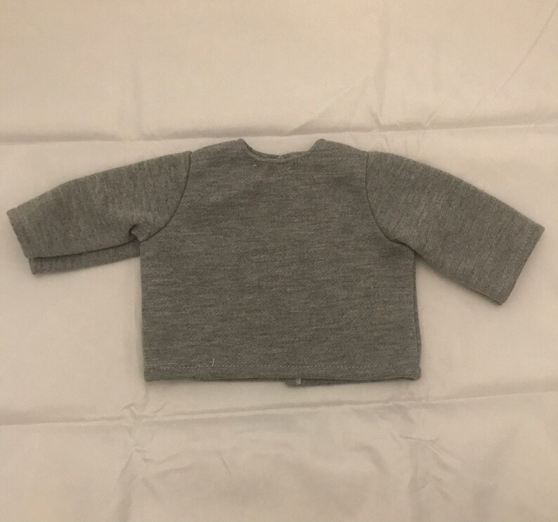 May include: A gray long-sleeved cardigan with a button closure.