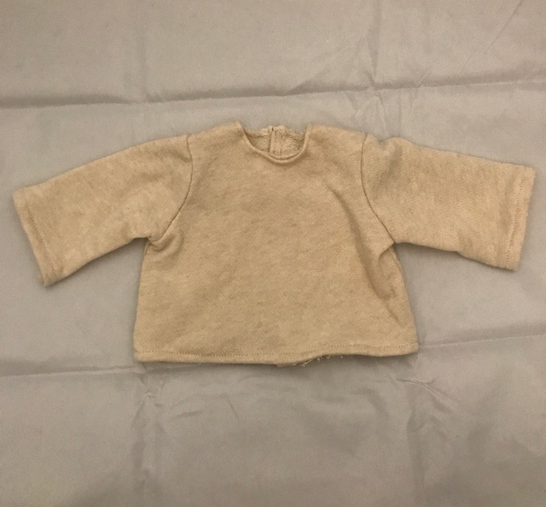 May include: A beige long-sleeved shirt with a round neckline.